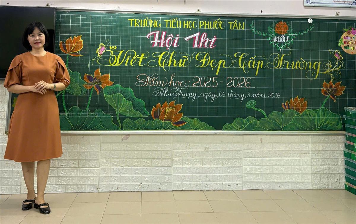 Cô Yến đứng cạnh tấm bảng Hội thi Viết chữ đẹp cấp trường, năm học 2025-2026
